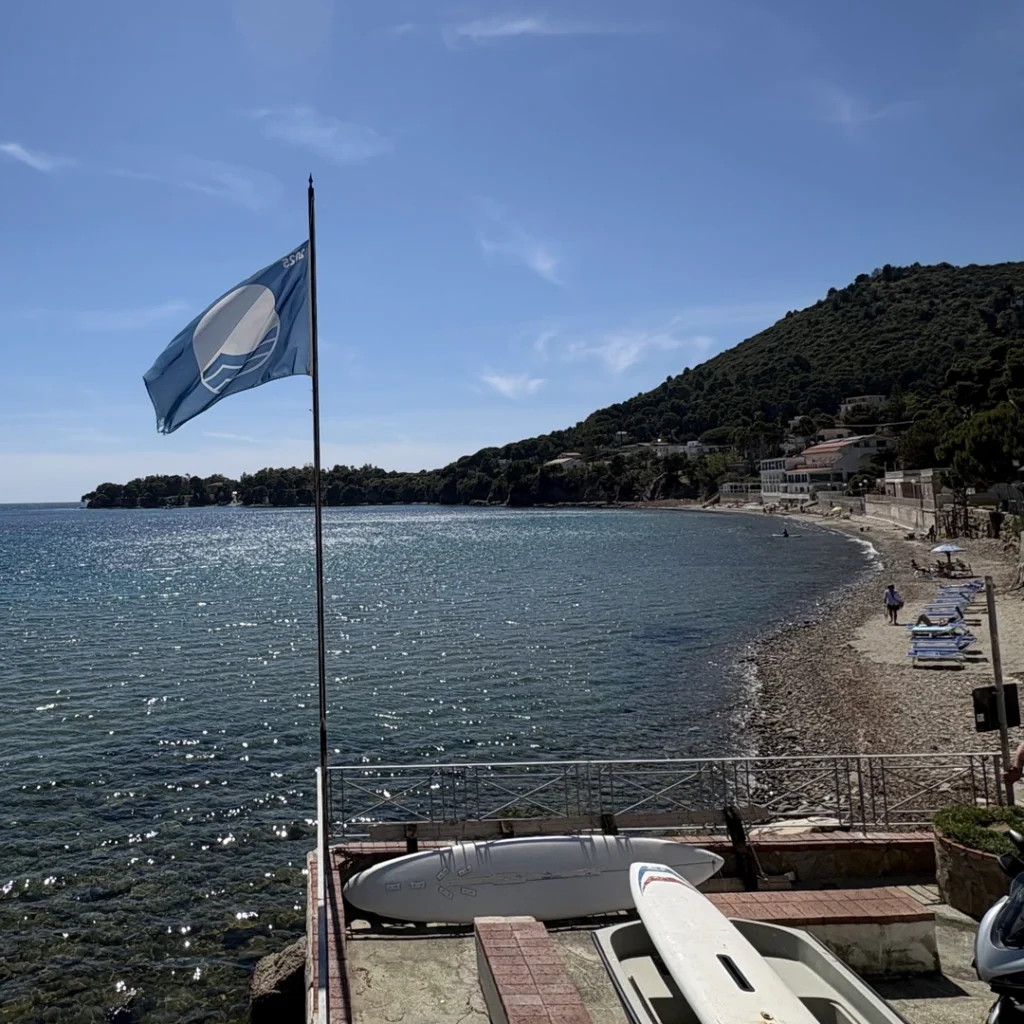 Bandiera Blu sul mare del Cilento con spiaggia e costa sullo sfondo